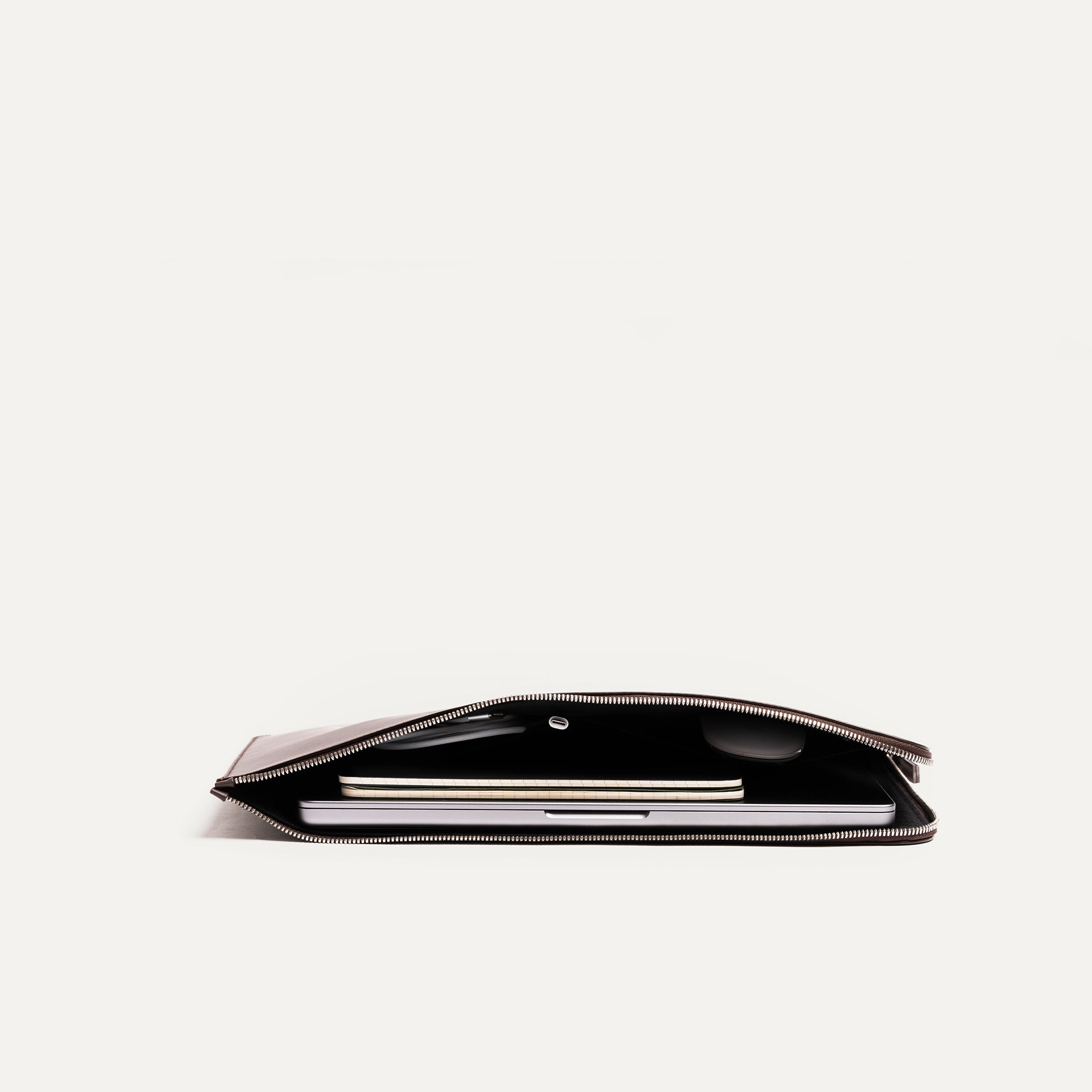 Cette pochette en cuir marron offre une protection fonctionnelle pour votre ordinateur portable. Son design compact et sa fermeture éclair supérieure en font un choix pratique. Elle possède également 2 poches à l'intérieur de la pochette pour transporter des accessoires en plus comme une souris d'ordinateur ou un chargeur. 