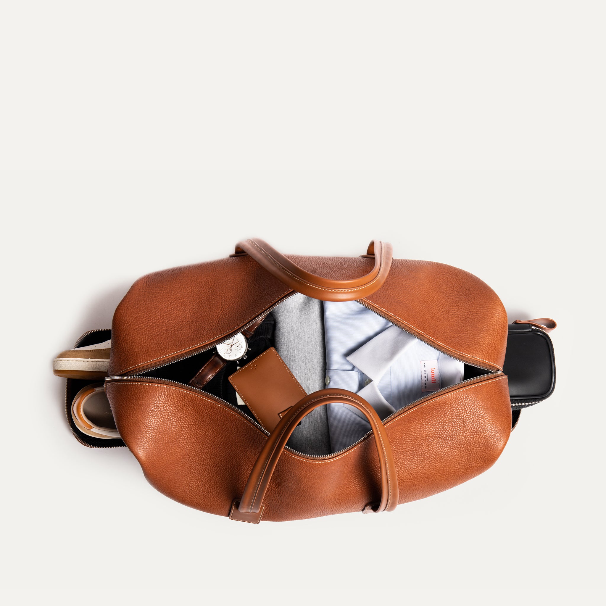 notre sac de voyage en cuir camel est conçu d'un espace rangement pour vos vêtements ainsi qu'un compartiment dédié pour vos chaussures, garantissant une organisation optimale et un espace pour ranger votre trousse de toilette. 