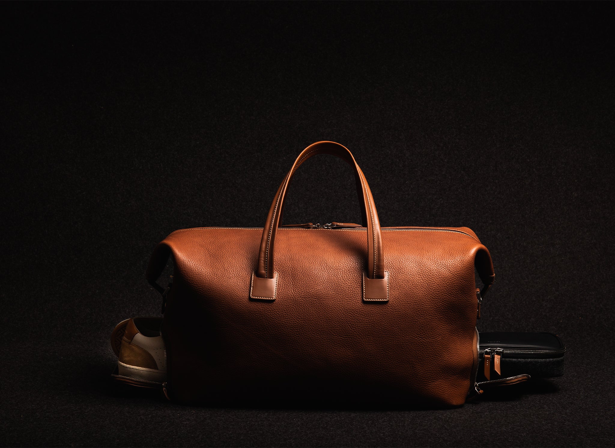 Ce sac à main en cuir cognac est parfait pour les voyages courts, offrant un compartiment pratique pour vos chaussures et votre trousse de toilette. Il est conçu pour les voyageurs qui apprécient le l'élégance et la fonctionnalité. Un choix idéal pour allier style et utilité.